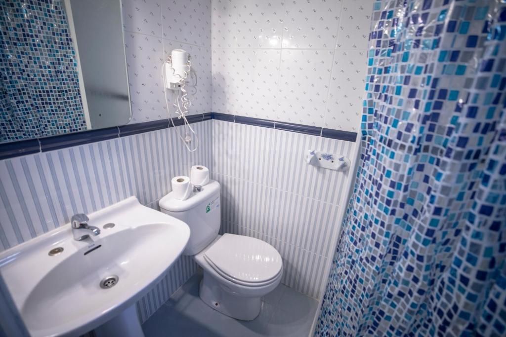 Un baño con lavabo, inodoro y cortina de ducha.