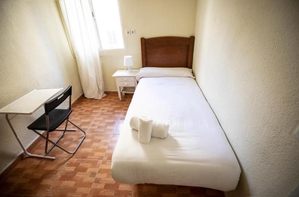 Un dormitorio con una cama individual, escritorio y silla.