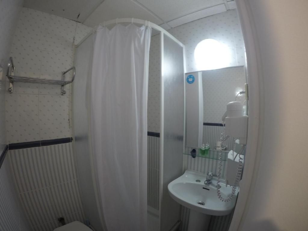 Un baño con ducha, lavabo, inodoro y espejo.