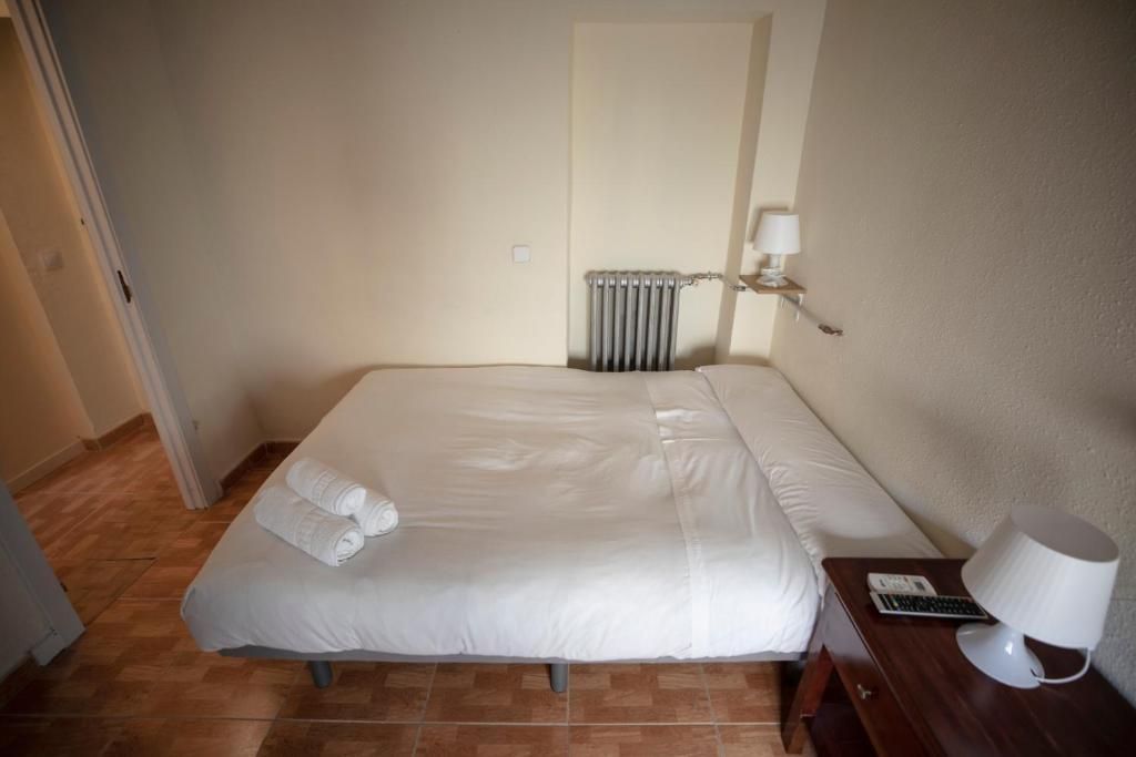 Un dormitorio con cama, mesita de noche, lámpara y radiador.