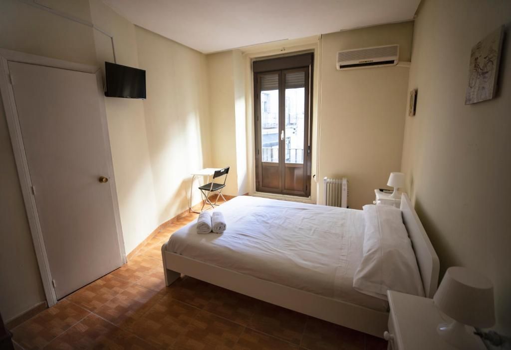 Un dormitorio con una cama grande, un escritorio, una televisión y un balcón.