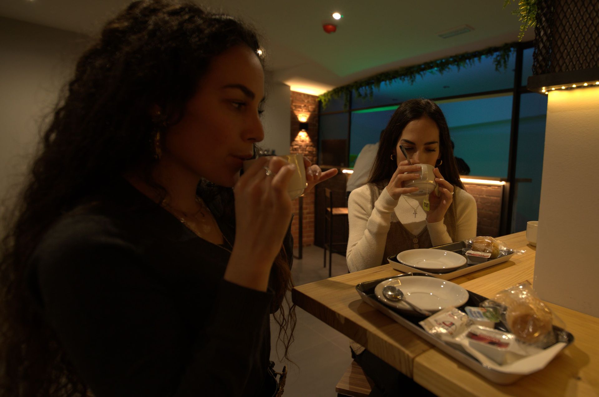 Dos mujeres están sentadas en una mesa tomando café.