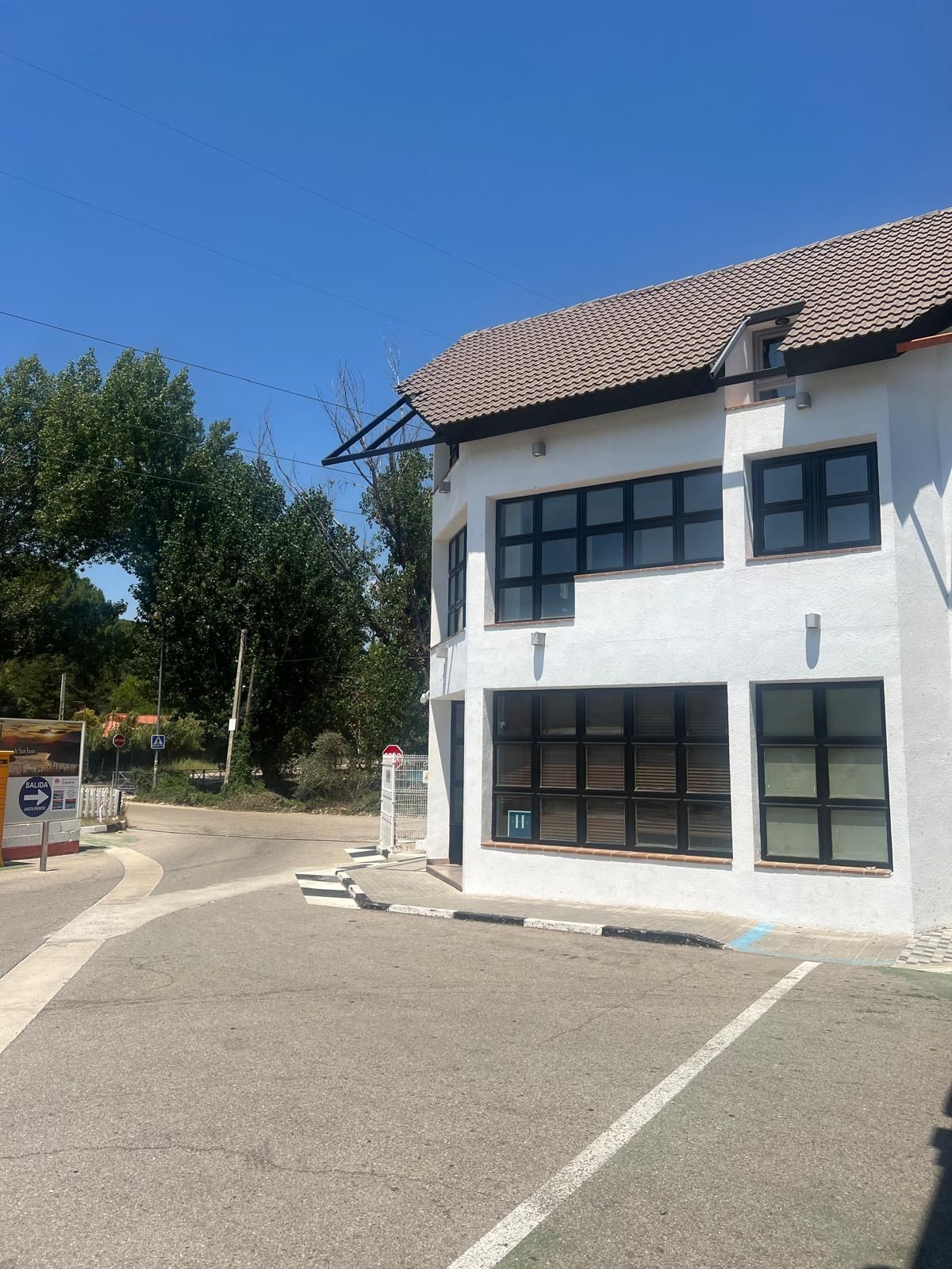 Un edificio blanco con techo de tejas y un estacionamiento frente a él.
