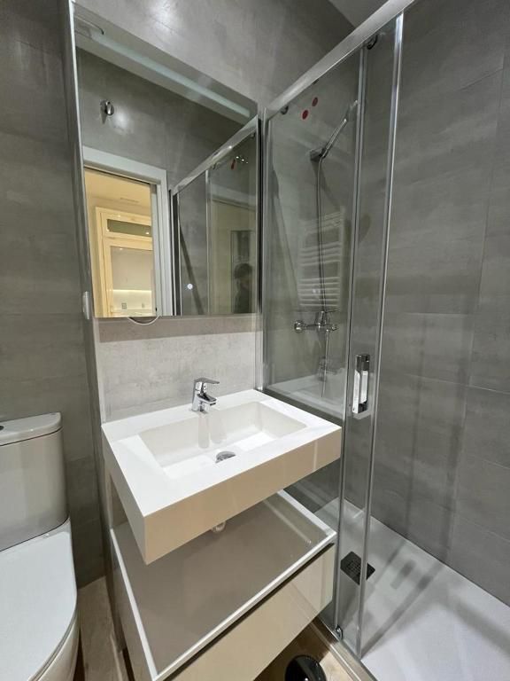 Un baño con lavabo, inodoro, ducha y espejo.