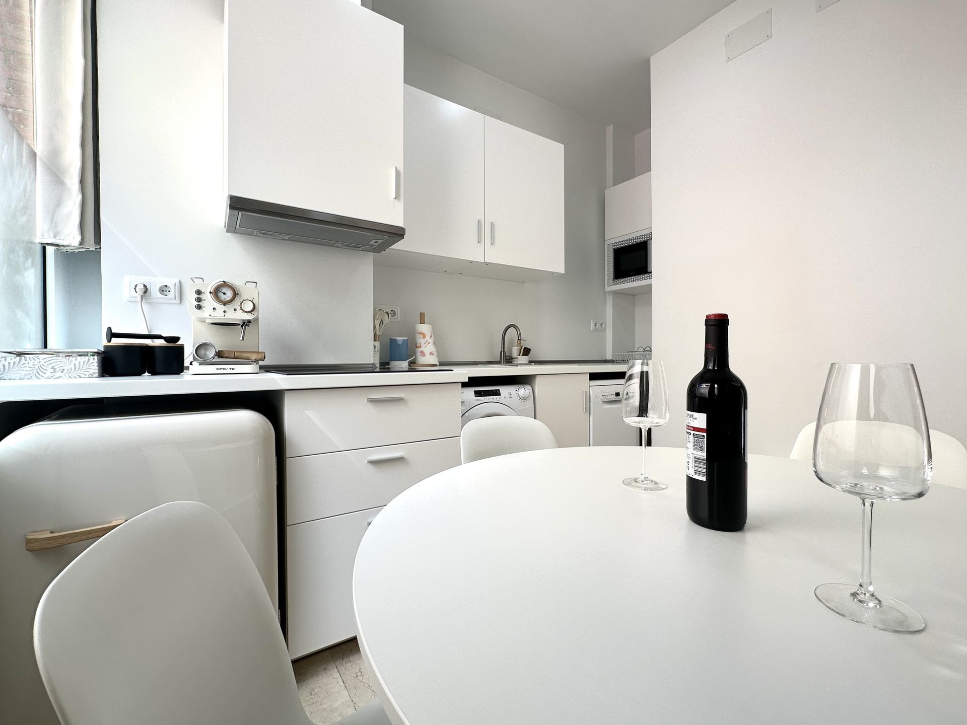 Una botella de vino y una copa de vino están sobre una mesa en una cocina.