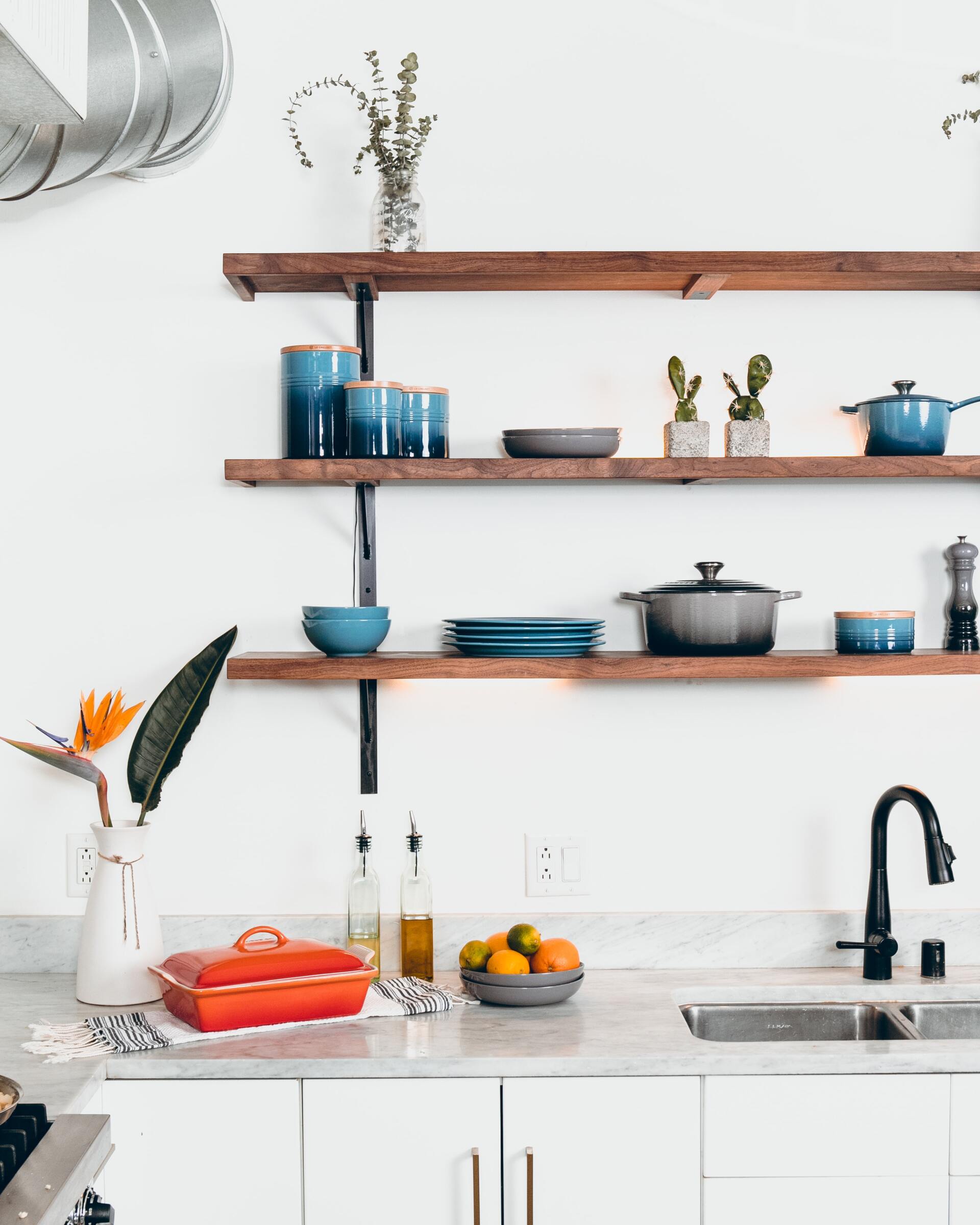 Una cocina con fregadero, ollas y sartenes en estantes.