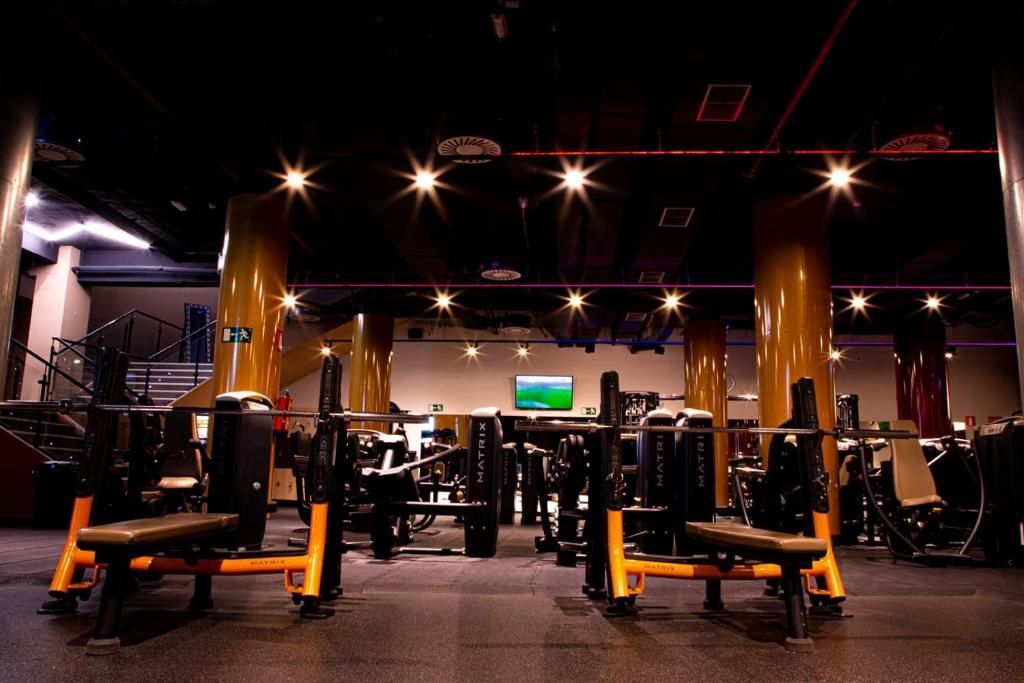 Un gimnasio con muchos equipos de ejercicio y un televisor en la pared.