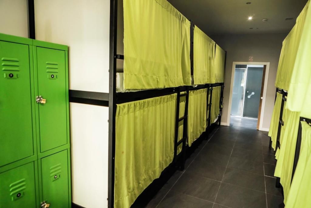 Un largo pasillo con taquillas verdes y cortinas amarillas.