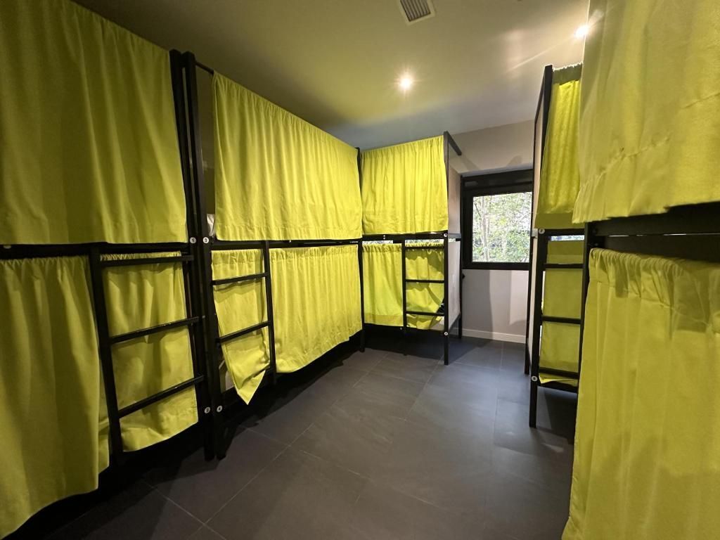 Una habitación llena de literas y cortinas amarillas.