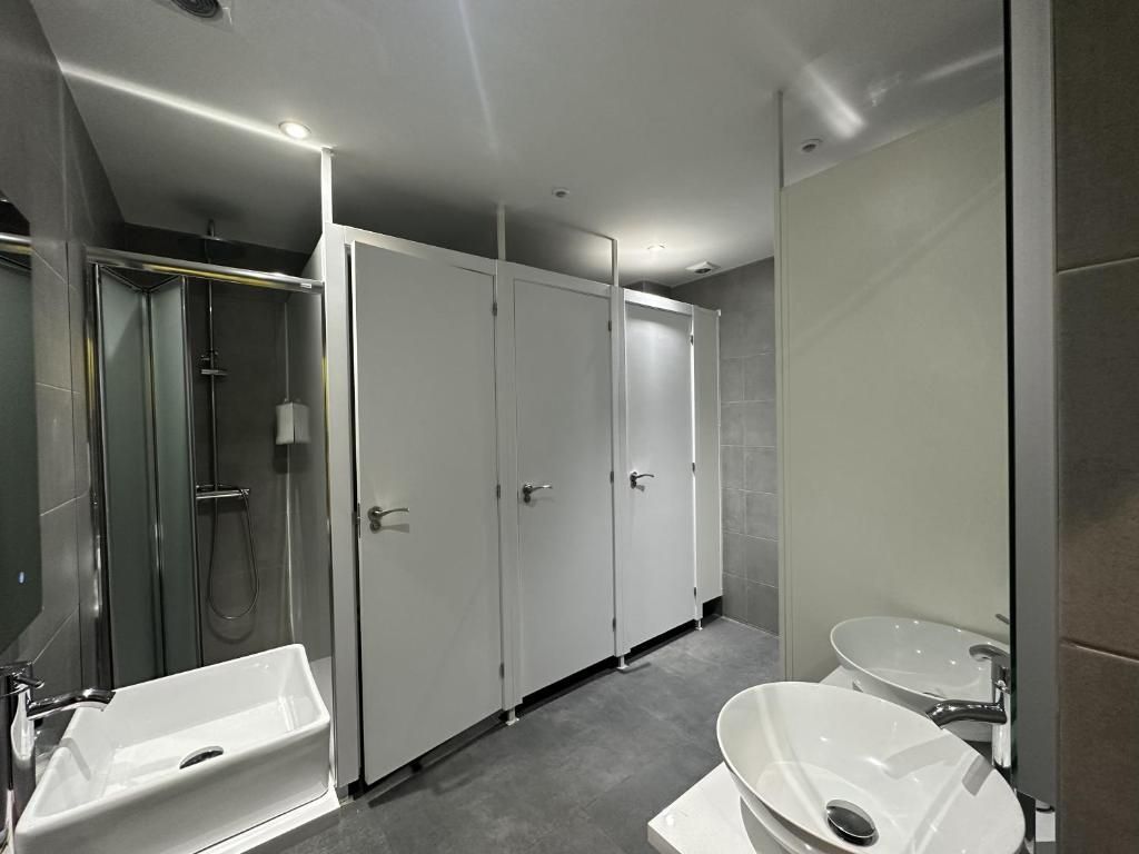 Un baño con dos lavabos, una ducha y un espejo.