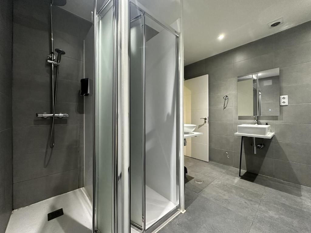 Un baño con ducha, lavabo y espejo.