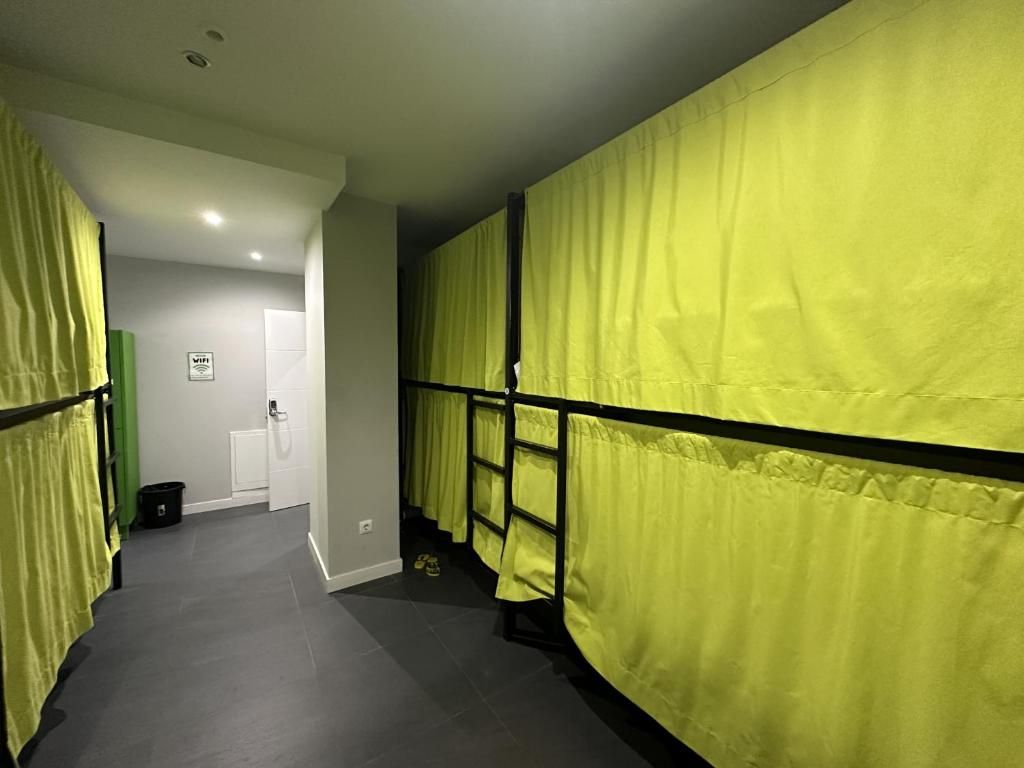 Una habitación con literas y cortinas amarillas en un albergue.