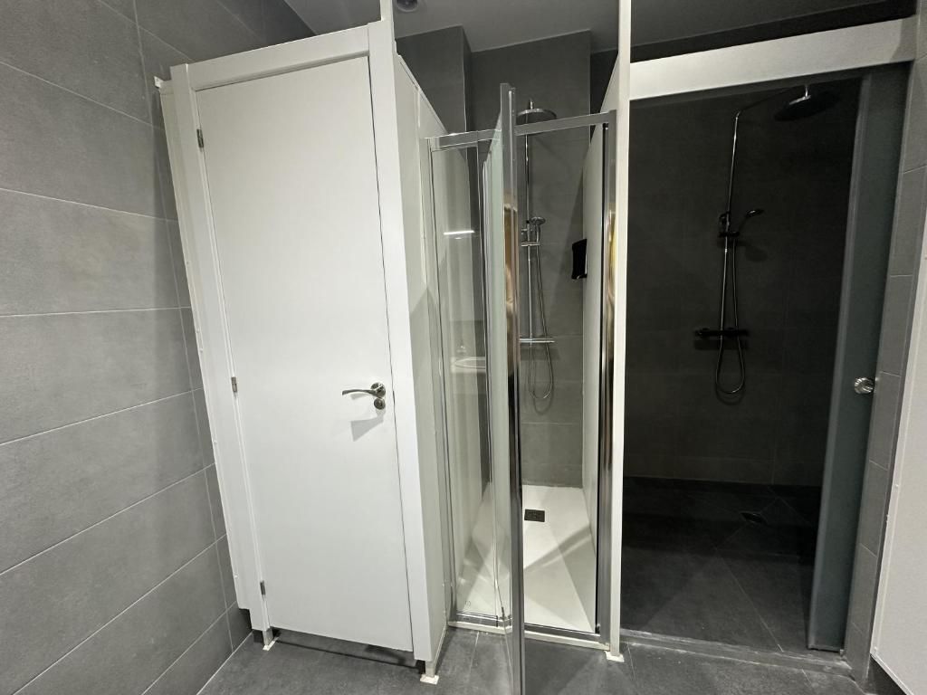 Un baño con dos cubículos y una cabina de ducha.
