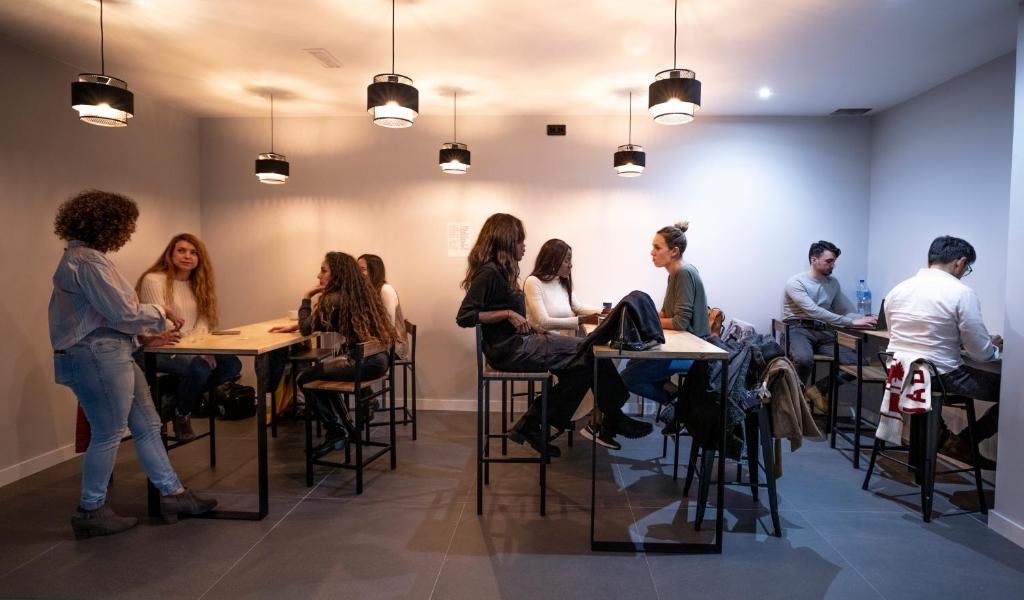 Un grupo de personas están sentadas en mesas en una habitación.