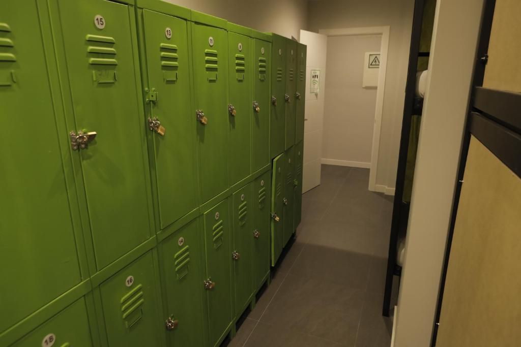 Un pasillo lleno de casilleros verdes y una puerta.