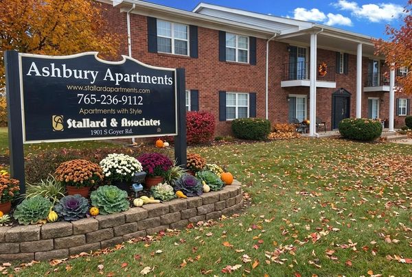 A brick apartment building with a sign in the foreground reading 