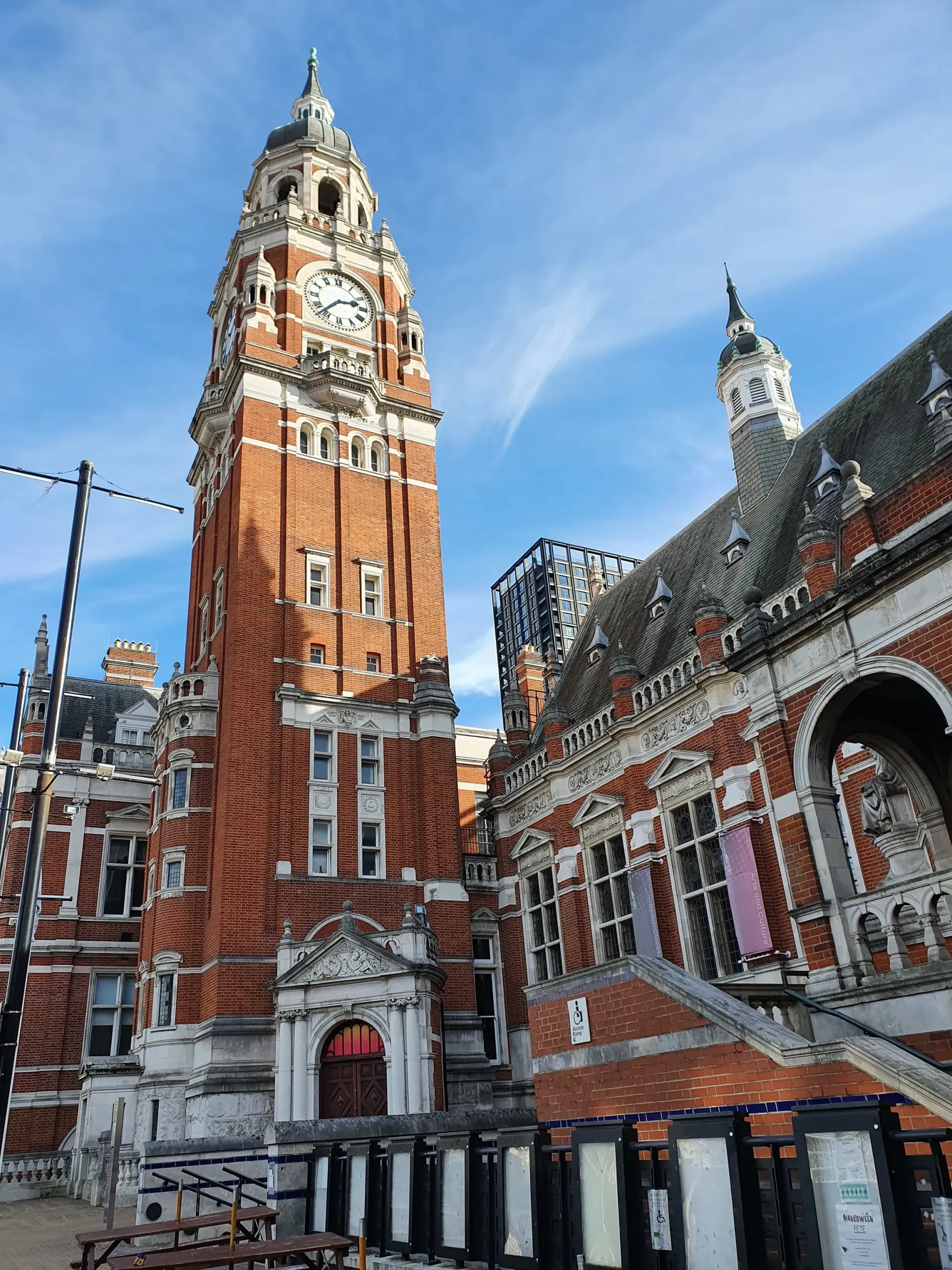 Red-brick historic clock tower and building under a blue sky with snow on the roof