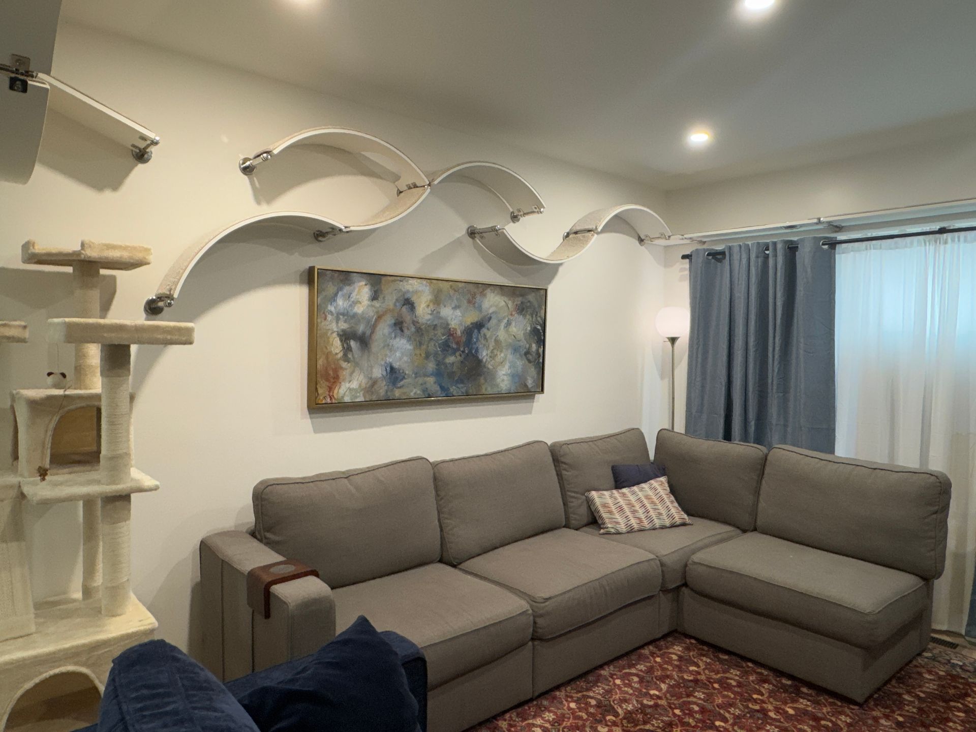 Modern living room featuring a custom CatScapes wall-mounted cat shelving system with curved cat shelves.