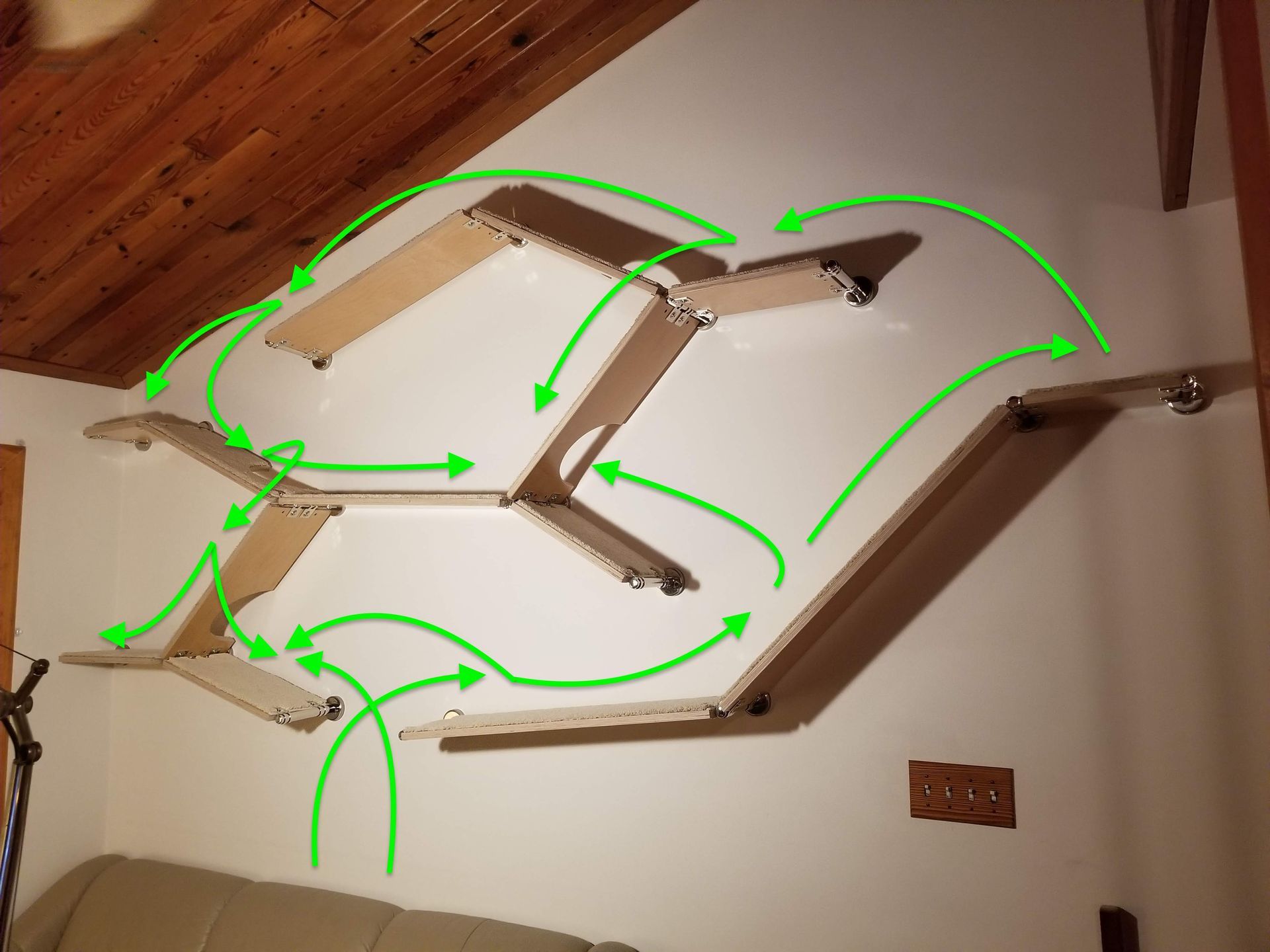 Multi-level modular cat shelf installation with green arrows indicating the directional climbing flow.