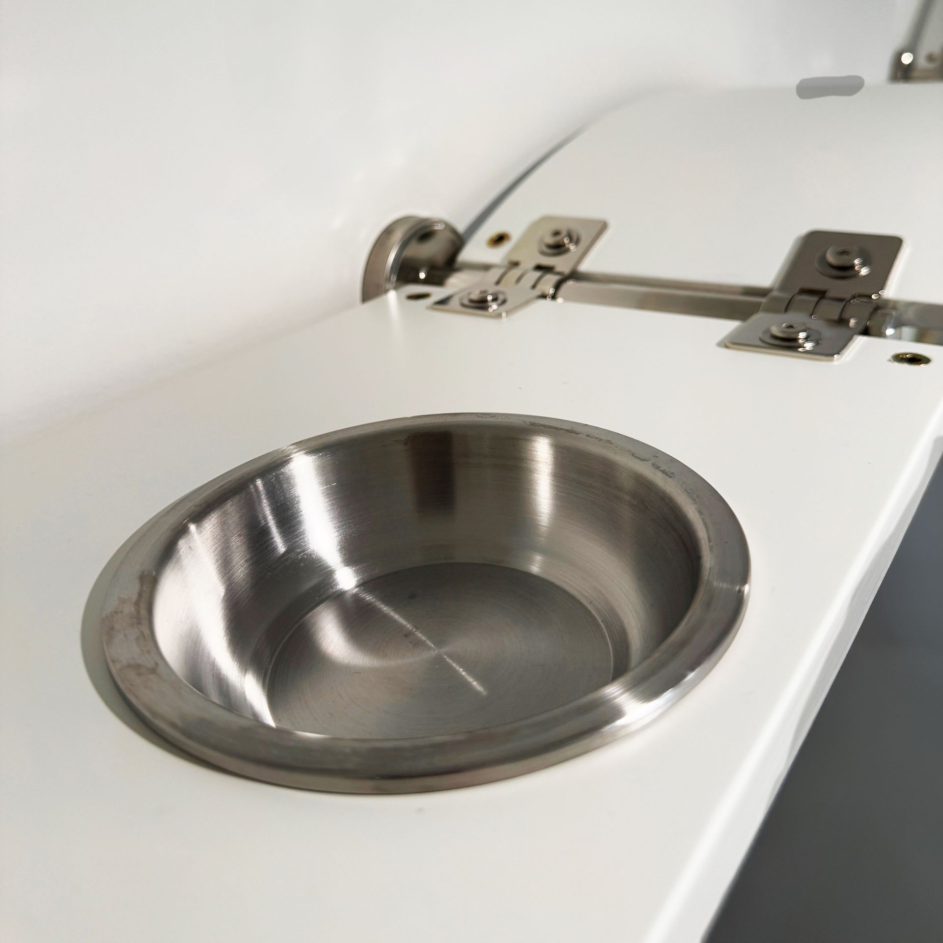 Close-up of wall-mounted Sky Diner cat feeding shelf featuring a white platform with a recessed stainless steel bowl.