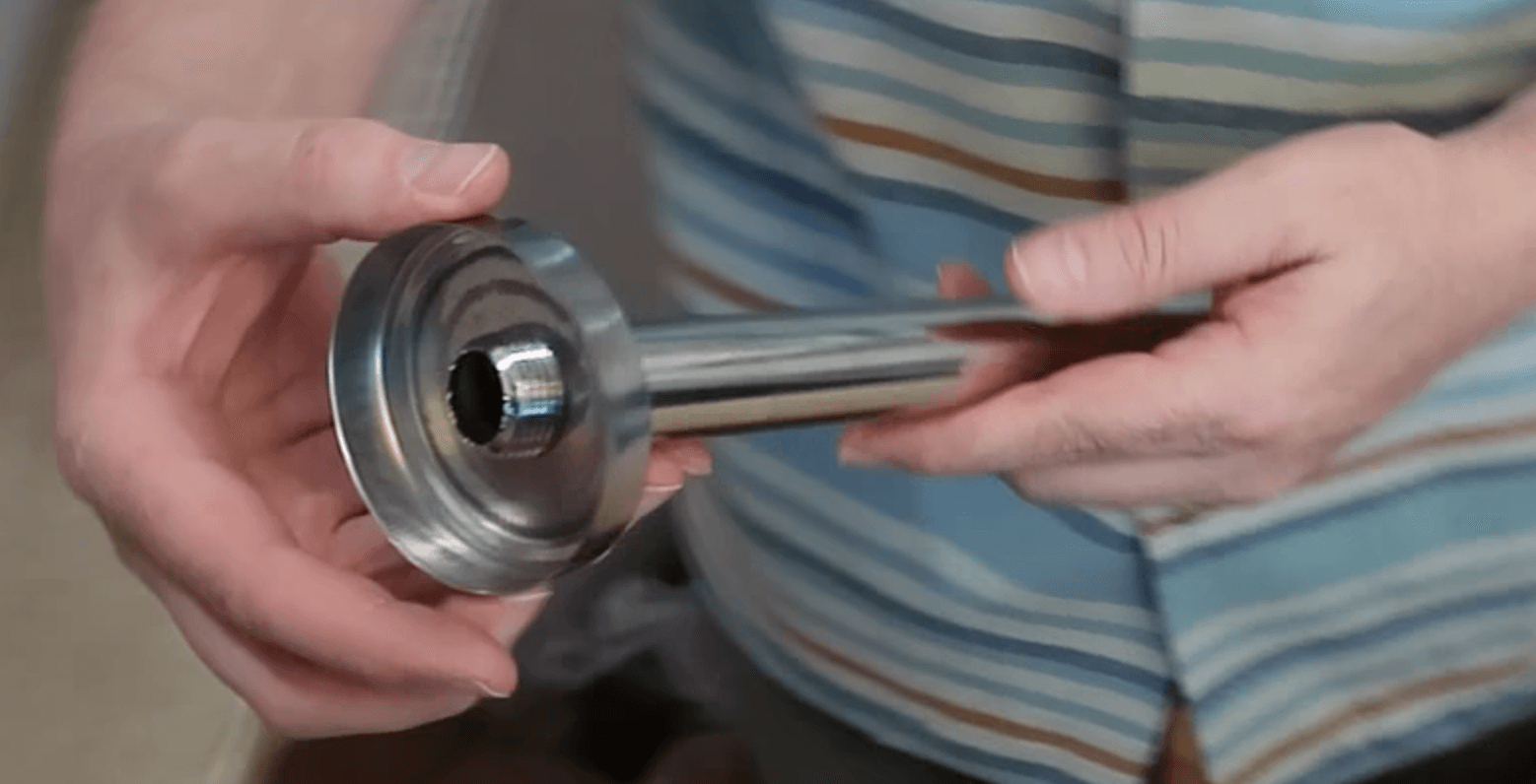 Close-up of hands holding a polished chrome mounting bracket arm with a circular wall flange base.