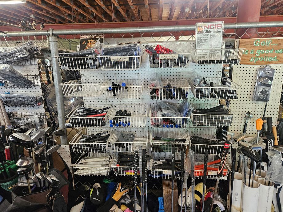 Indoor shop display of hanging tools and hardware on wire racks, with a cluttered workbench below.