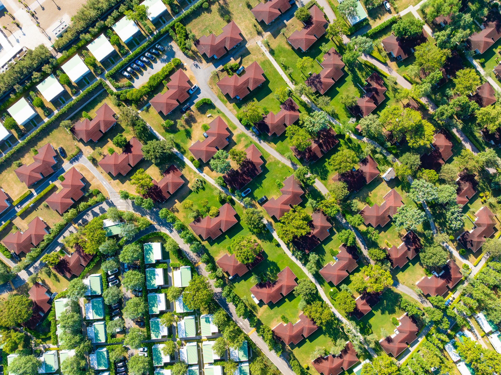 Aerial view of a neighborhood with brown-roofed houses and green trees.