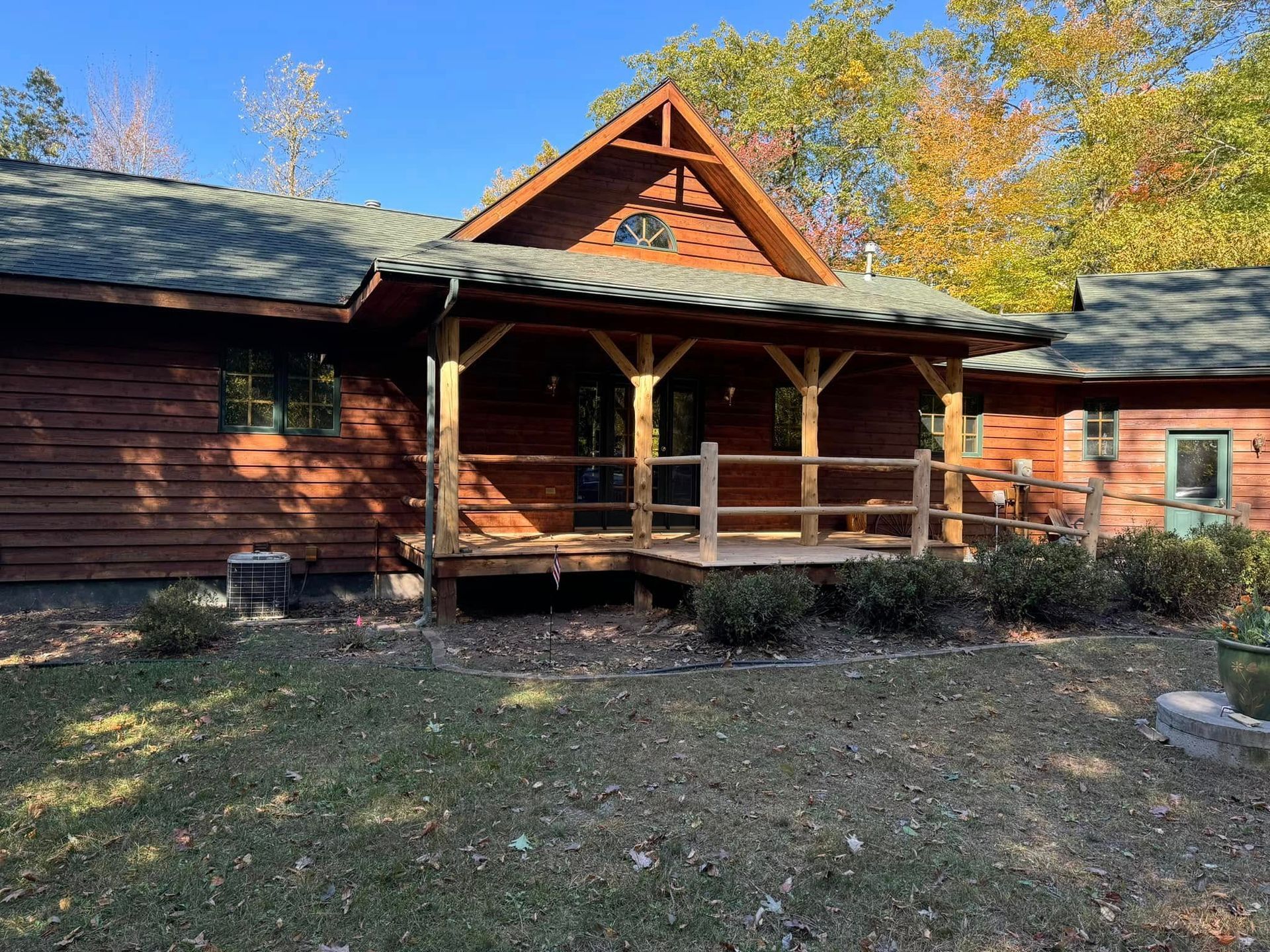 Rustic wooden cabin with a covered porch and autumn trees in the background