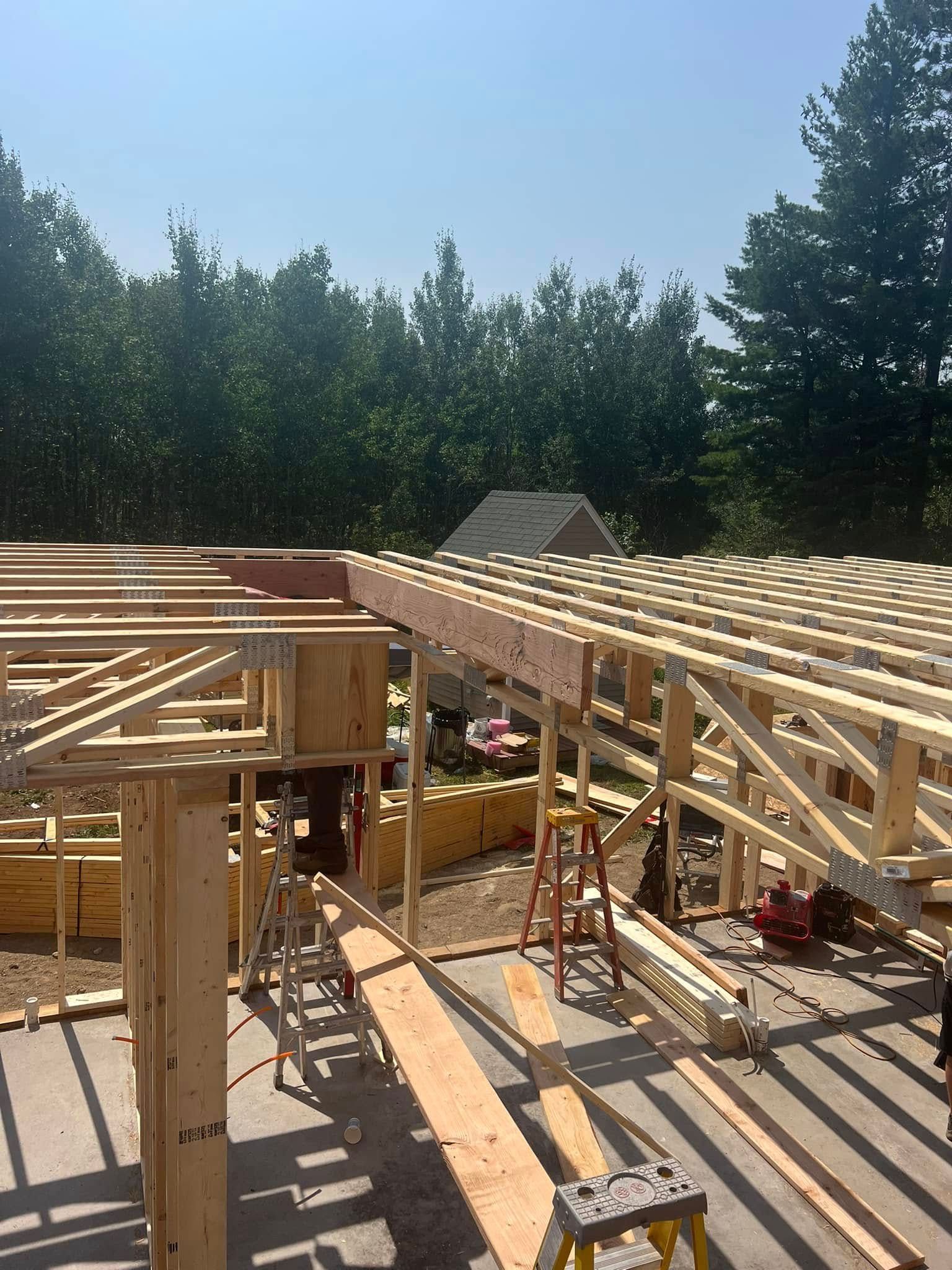 Partially framed wooden house under construction in a sunny wooded area