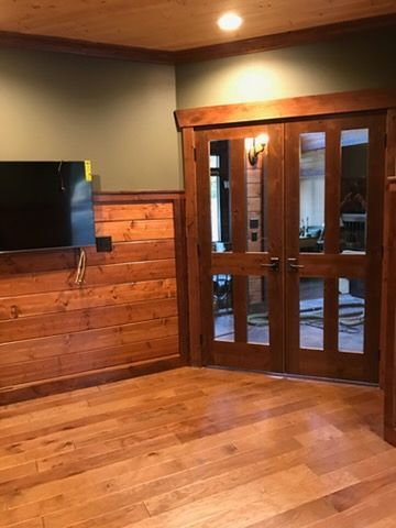 Wood-paneled room with wall-mounted TV and glass double doors leading outside.