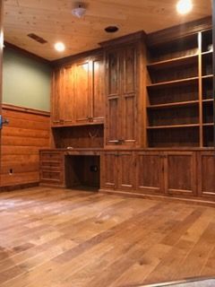 Wood-paneled room with built-in cabinets, shelves, and hardwood floors