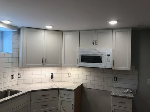 Modern kitchen with gray cabinets, white subway tile backsplash, and built-in microwave above the counter.