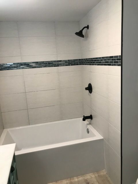 Small tiled bathroom with a white bathtub and black shower fixtures