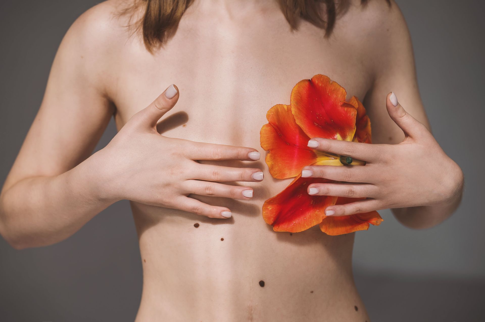 Mulher com uma flor na frente dos seios representando câncer de mama e mastectomia