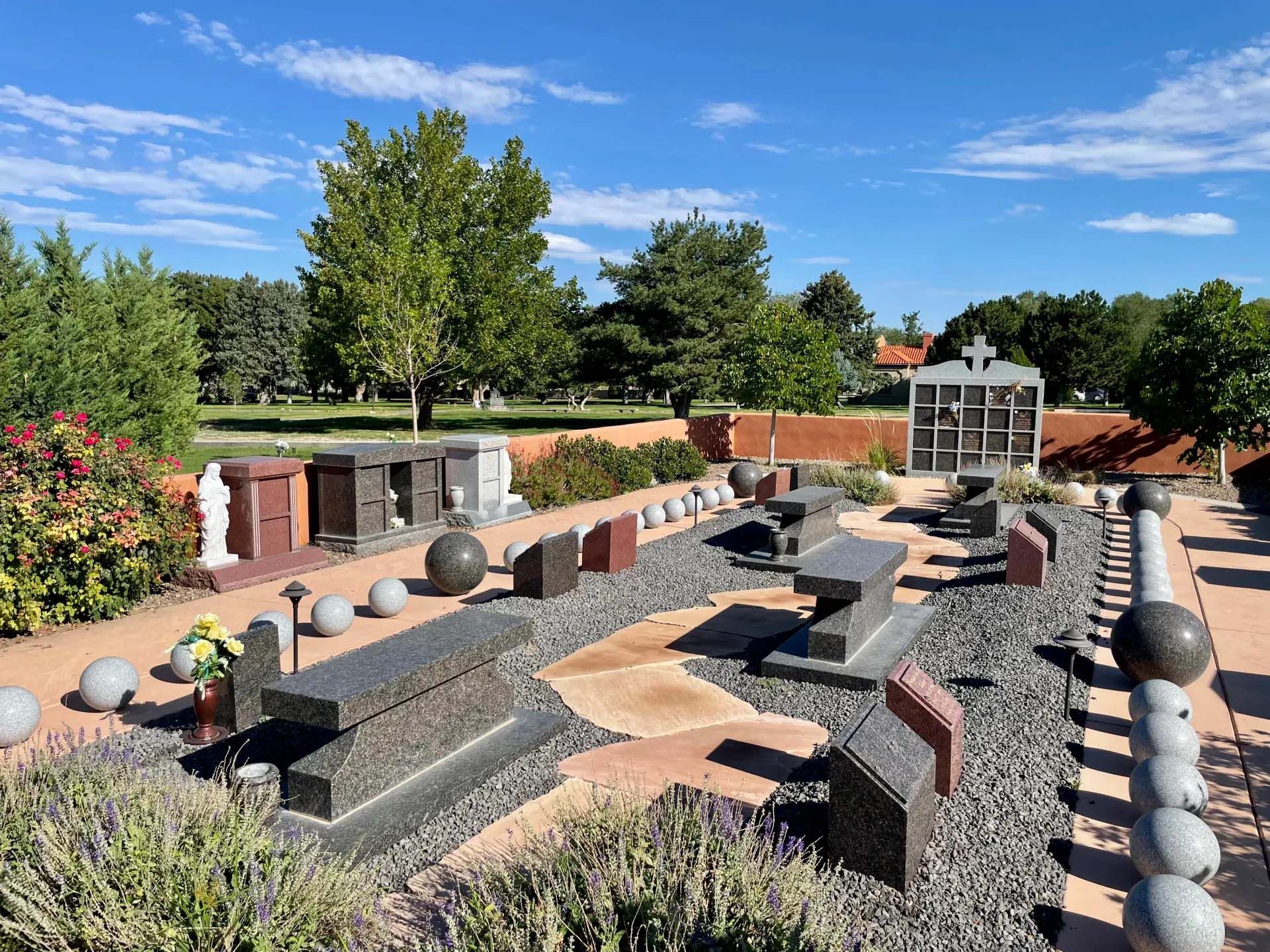 Outdoor display of gravestones in a park-like setting under a blue sky.