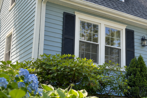 White house siding and trim beside gray horizontal siding against a blue winter sky