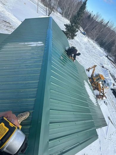 green metal roof install with a working installing panels in maine