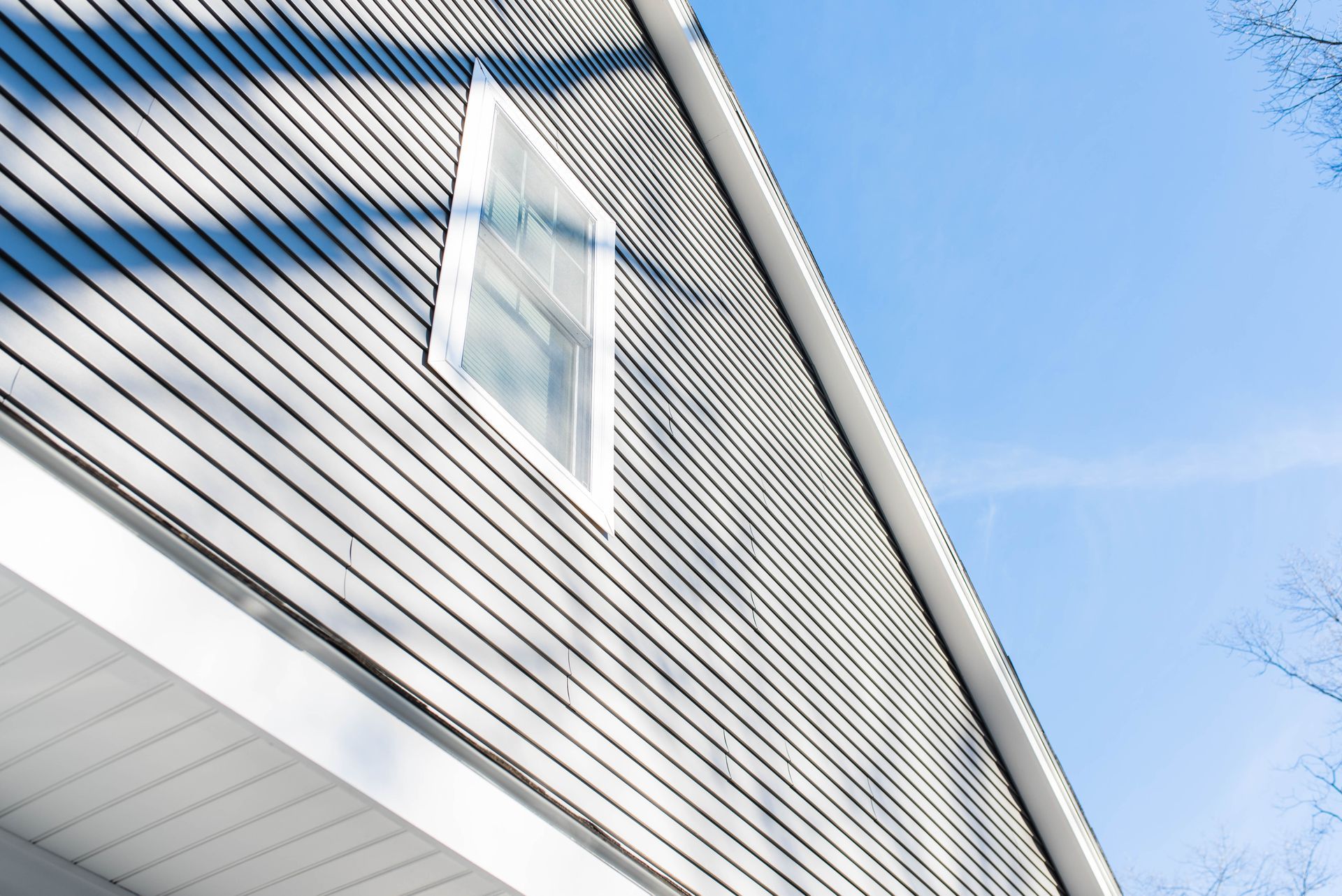 White house siding with a dormer window against a blue sky