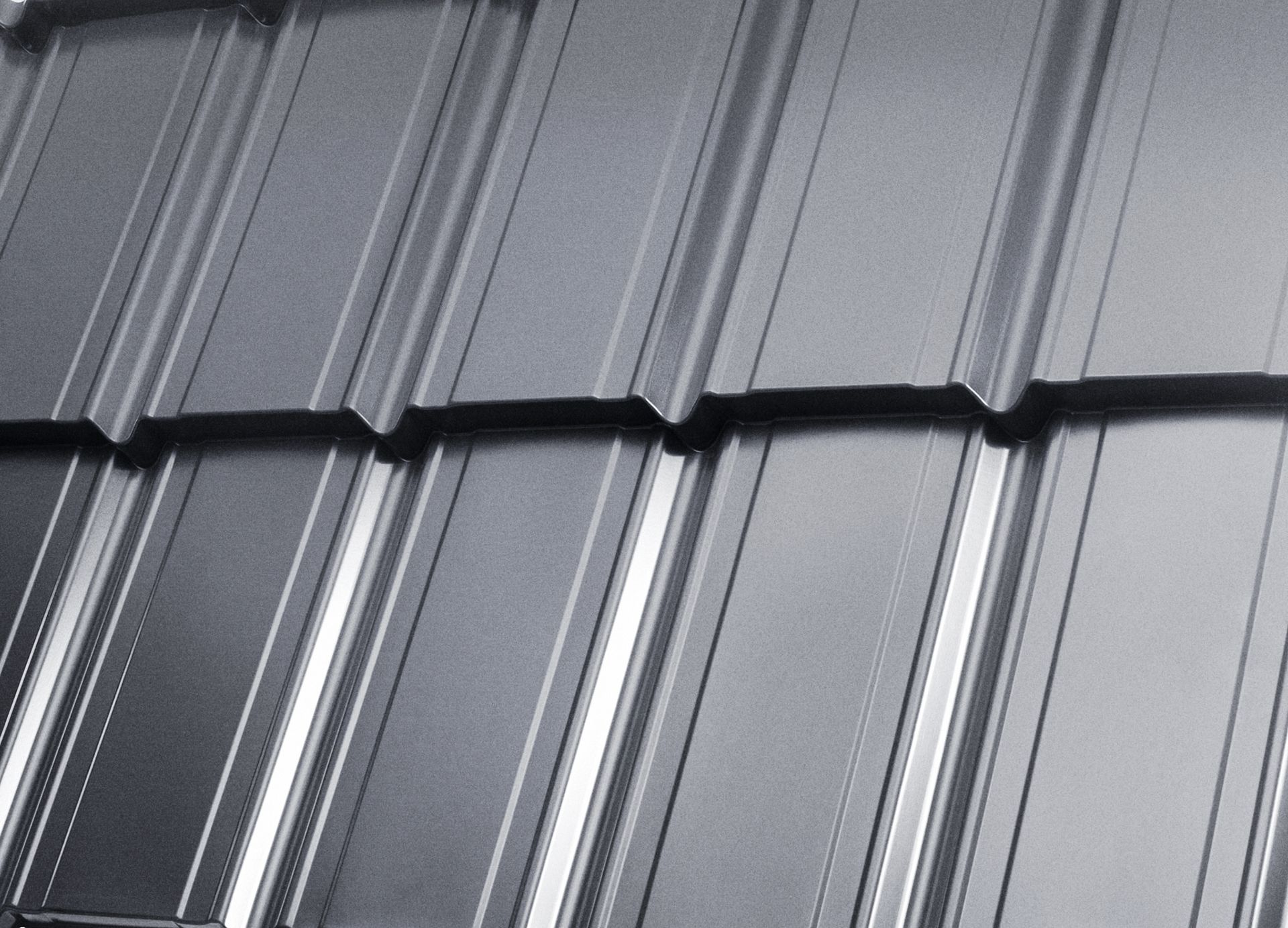 Close-up of gray metal roof panels with raised seams and glossy reflections