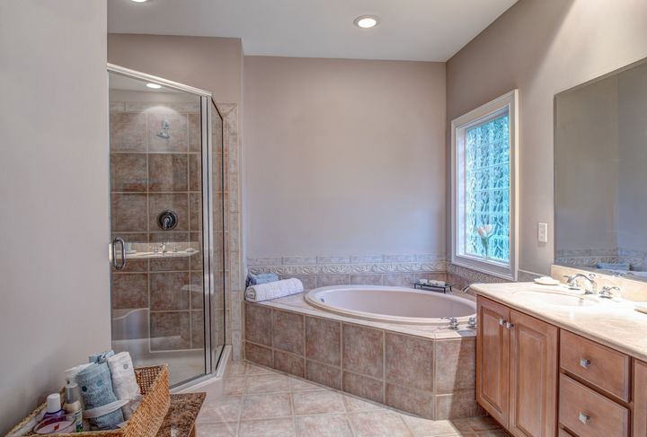 Bathroom with corner shower, built-in tub, vanity, and a window with a view.