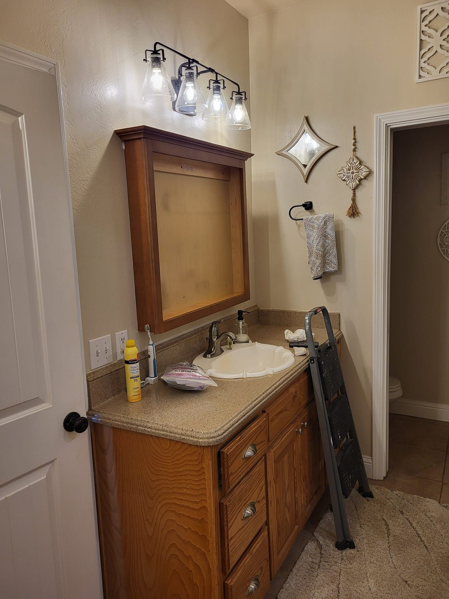 Bathroom vanity with mirror, lighting, and sink, with a step ladder next to it.