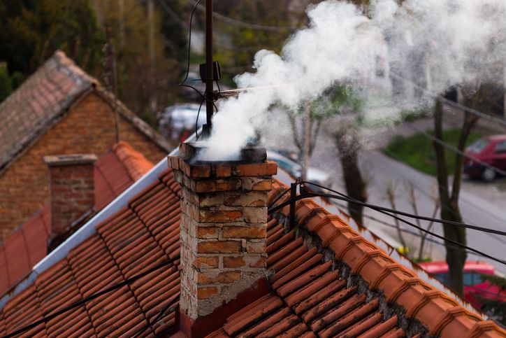 Smoke is coming out of a chimney on a roof.
