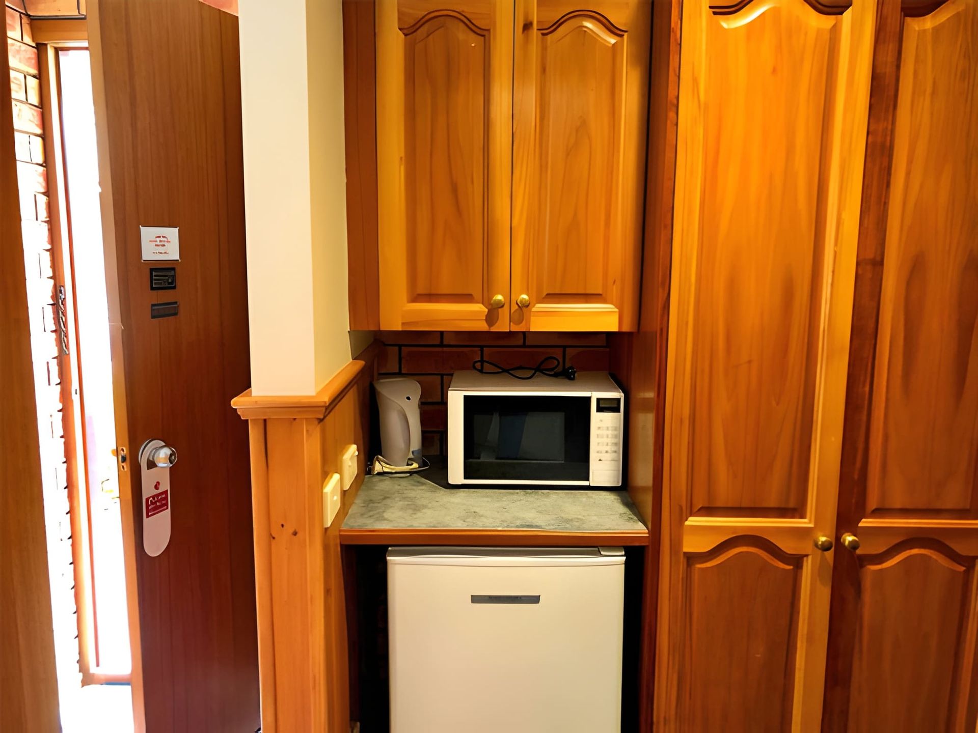 Kitchen cabinet nook with a microwave, mini fridge, and coffee maker beside a door