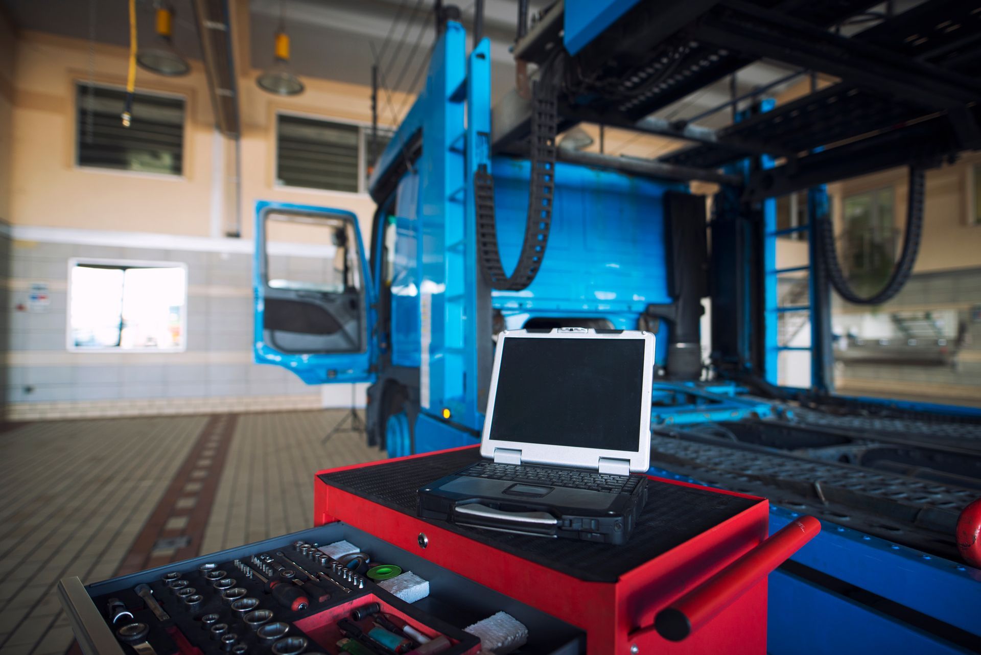 Industrial machine with a laptop on a red cart in a workshop