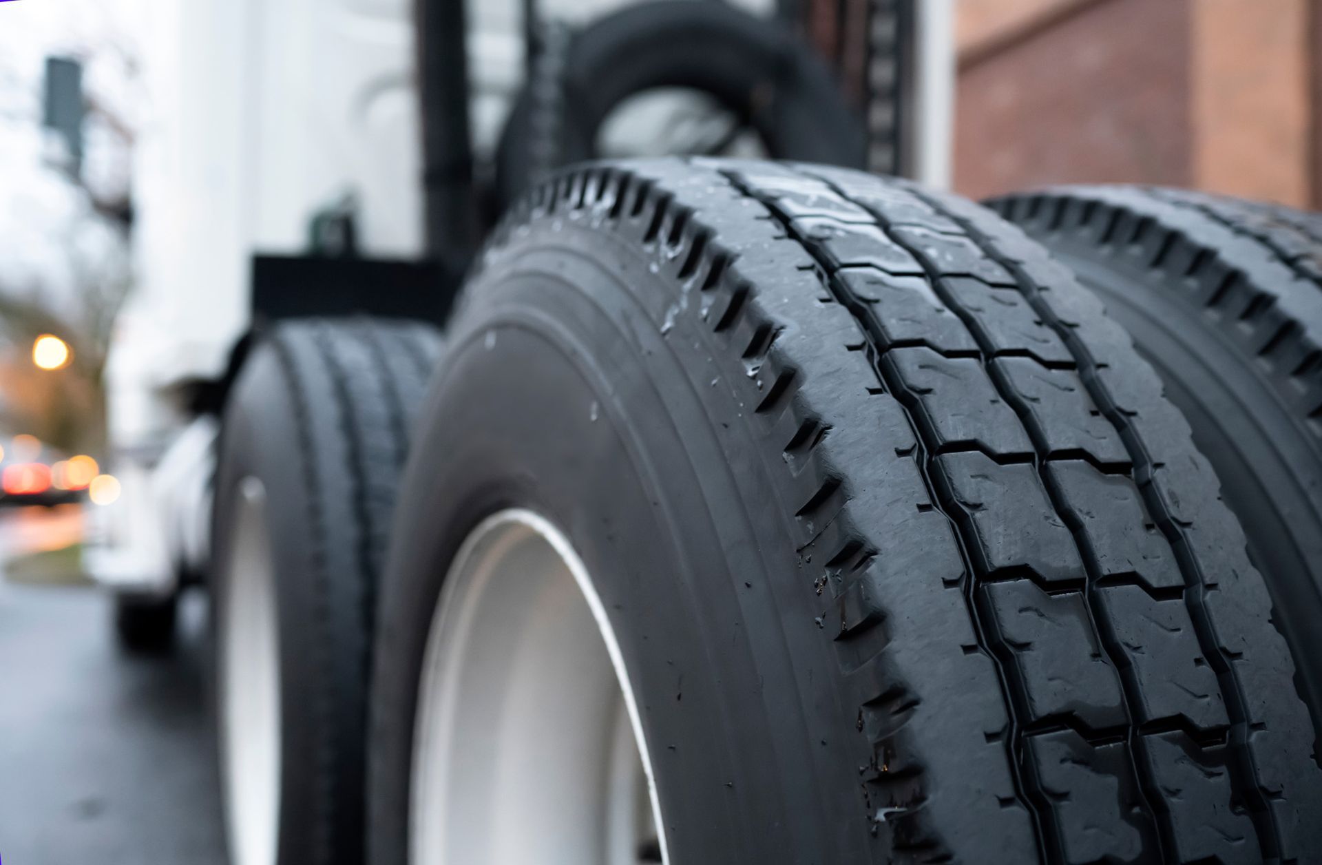 Close-up of large black truck tires on a vehicle parked along a city street