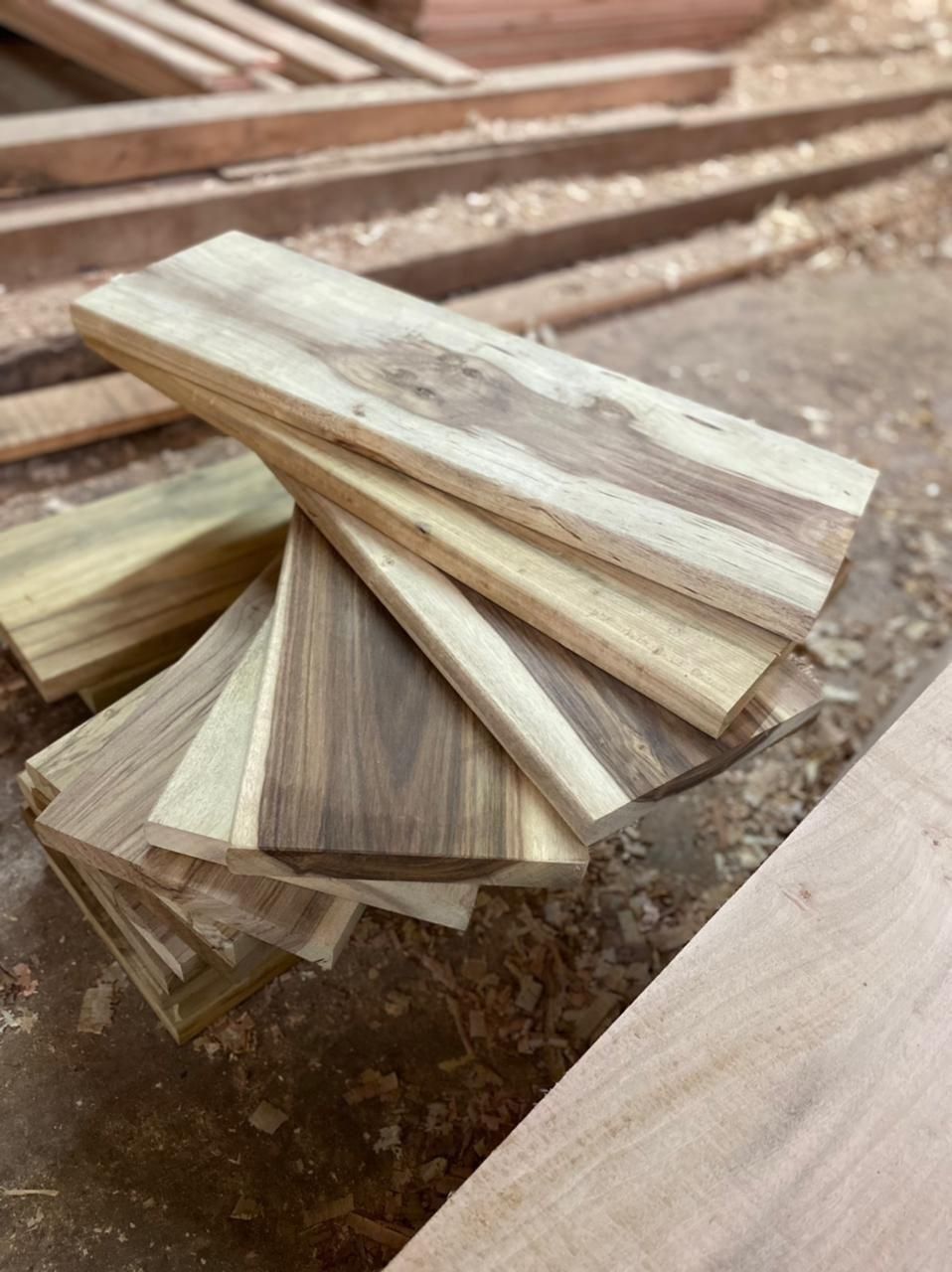 Pila de listones de madera clara extendidos sobre un banco de trabajo rústico en un taller de carpintería.