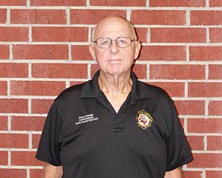 A picture of Commissioner Royce Sunday wearing glasses and a black shirt with a HCESD25 logo patch.
