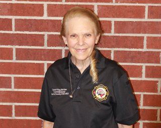 A picture of Commissioner Carol King McGee wearing a black shirt with a HCESD25 logo patch.