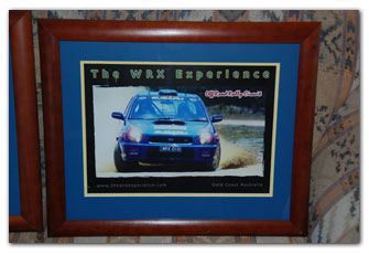 Framed blue Subaru rally car, kicking up dust, 