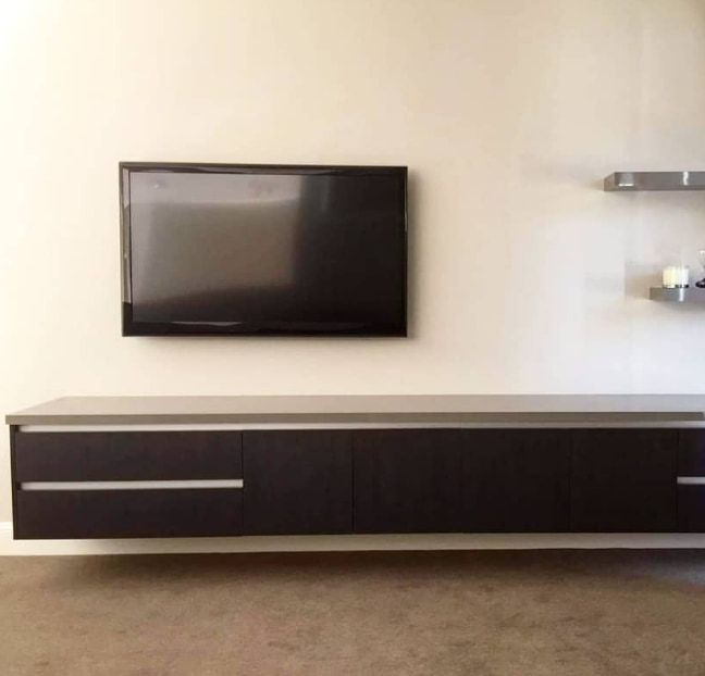 A Flat Screen Tv is Mounted on a Wall Above a Wooden Entertainment  — Truline Cabinets In Tuchekoi, QLD
